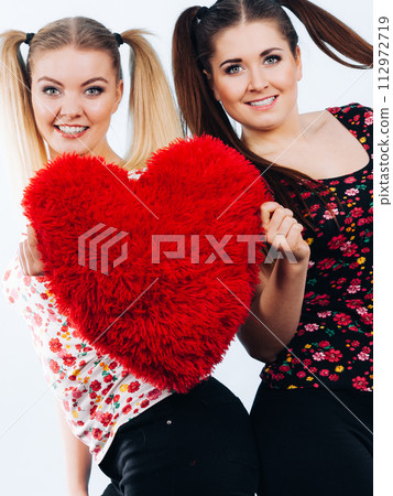 Happy two women holding heart shaped pillow 112972719