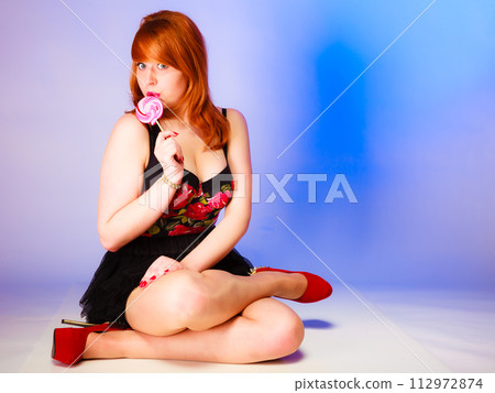 Carefree woman eating lollipop. Carefree woman eating lollipop. 112972874
