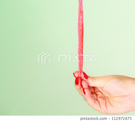 Female hand holding sweet food jelly candy on green. 112972875