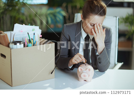 female employee in green office putting coin into piggy bank 112973171