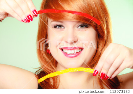 Redhair girl holding sweet food jelly candy on green. 112973183