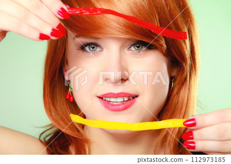 Redhair girl holding sweet food jelly candy on green. 112973185