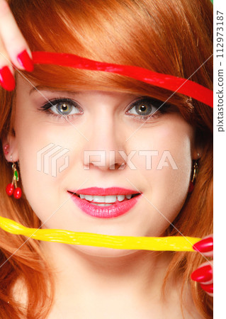 Redhair girl holding sweet food jelly candy on green. 112973187