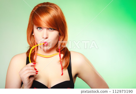 Redhair girl holding sweet food jelly candy on green. 112973190