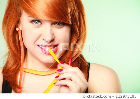 Redhair girl holding sweet food jelly candy on green. 112973193