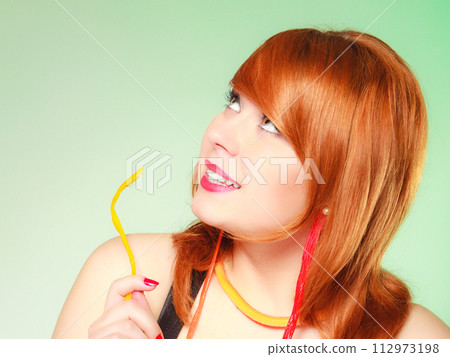 Redhair girl holding sweet food jelly candy on green. 112973198