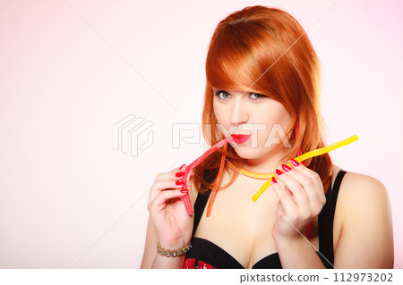 Redhair girl holding sweet food jelly candy on pink. 112973202