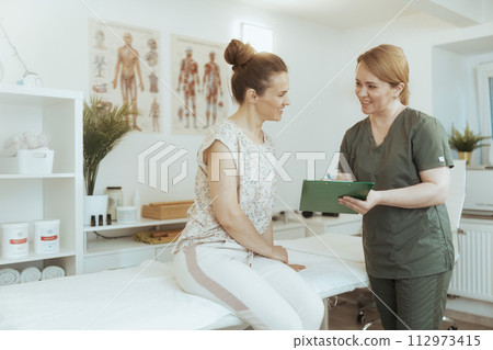 female therapist conducting examination and writing in clipboard 112973415