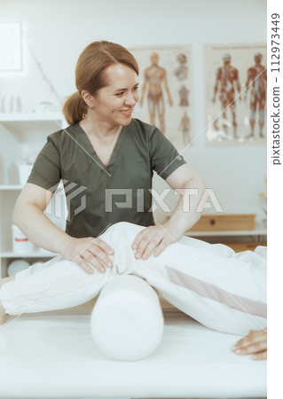 smiling female therapist in massage cabinet doing checkup 112973449