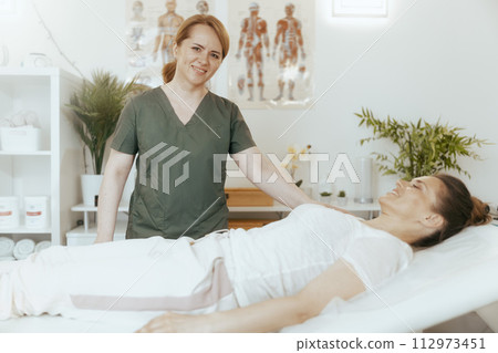 smiling therapist woman in massage cabinet doing checkup smiling therapist woman in massage cabinet doing checkup 112973451