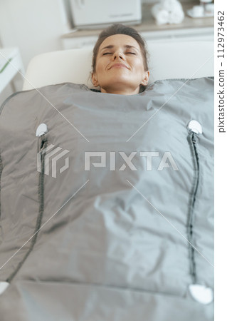 woman doing whiskey swaddling procedure in thermal blanket 112973462