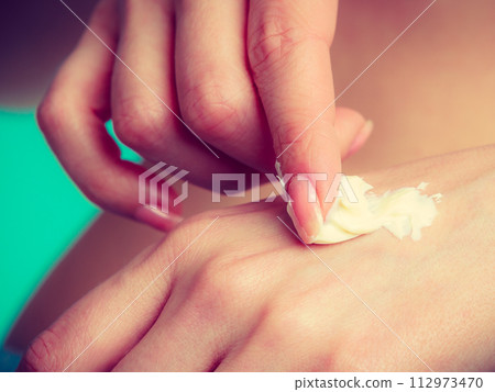 Woman putting white cream on hand 112973470