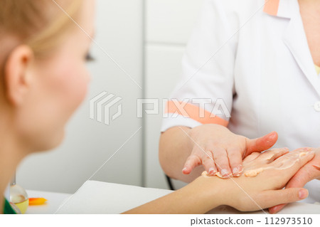 Woman applying cream on hand using spatula 112973510