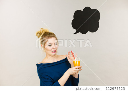 Disgusted woman holding orange juice 112973523