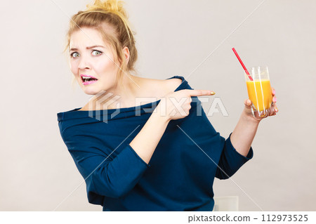 Disgusted woman holding orange juice Disgusted woman holding orange juice 112973525