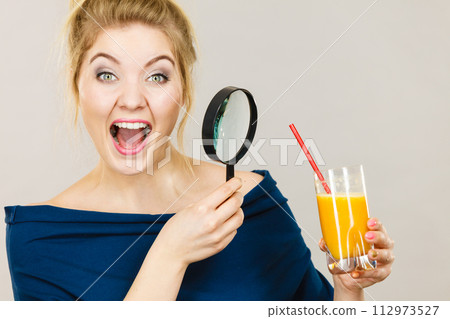 Woman holding magnifying glass investigating juice 112973527