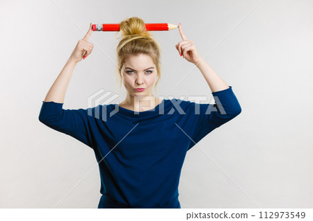 Confused blonde woman having big pencil in hair Confused blonde woman having big pencil in hair 112973549