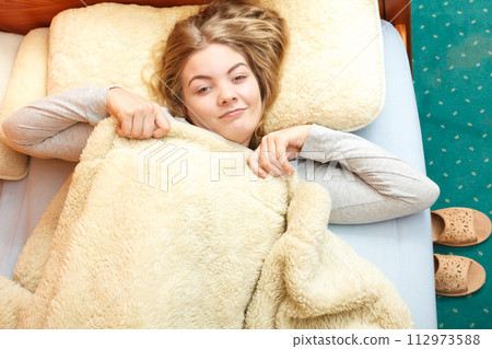 Woman waking up in bed in morning after sleeping 112973588
