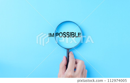 Hand holding magnifying glass focuses on possible from the word impossible on a light blue background. possible motivational inspirational, Business metaphor concept, looking on good side, optimism, Hand holding magnifying glass focuses on possible from the word impossible on a light blue background. possible motivational inspirational, Business metaphor concept, looking on good side, optimism, 112974005