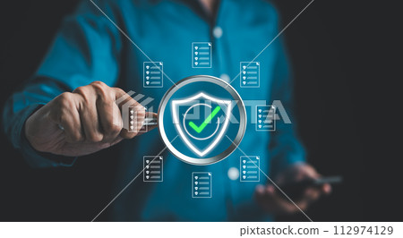 Businessman holding magnifying glass with standard quality control certification assurance guarantee for automation process. Quality management, Quality Assurance, Standardization, health insurance, 112974129