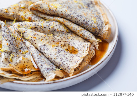 Crepes with poppy seeds, maple syrup and zest. 112974140