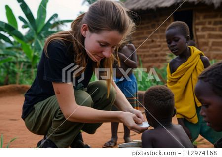 Female volunteer helps children in African village 112974168
