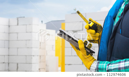 A foreman stands with a board and tape measure. A foreman stands with a board and tape measure. 112974606