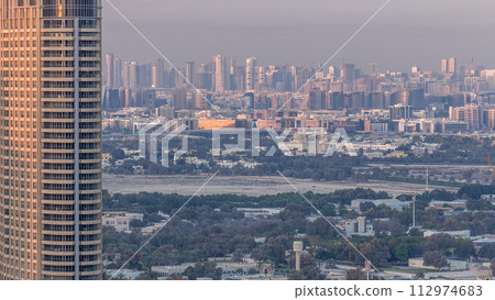 Skyline view of Deira and Sharjah districts in Dubai timelapse at sunset, UAE. 112974683