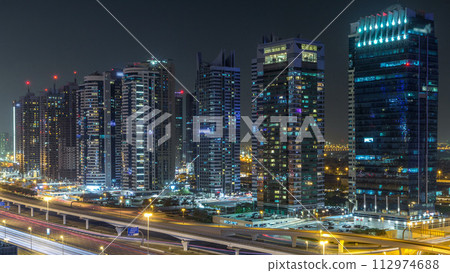 Aerial view of Jumeirah lakes towers skyscrapers during all night timelapse with traffic on sheikh zayed road. Aerial view of Jumeirah lakes towers skyscrapers during all night timelapse with traffic on sheikh zayed road. 112974688
