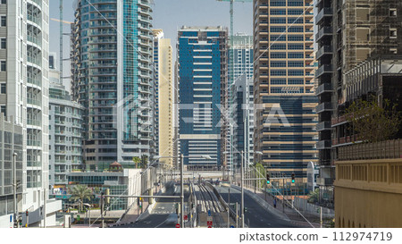 Dubai Marina with Skyscrapers timelapse and traffic on the street near concrete road bridge through the canal 112974719