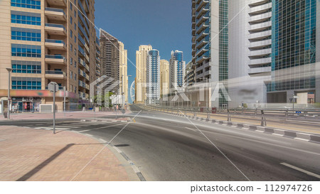 Dubai Marina with Skyscrapers timelapse hyperlapse and traffic on the street near concrete road bridge through the canal Dubai Marina with Skyscrapers timelapse hyperlapse and traffic on the street near concrete road bridge through the canal 112974726