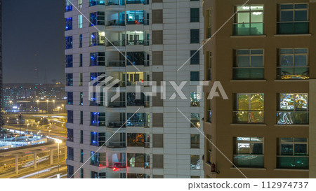 Windows of the multi-storey building of glass and steel lighting inside and moving people within timelapse 112974737