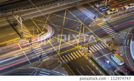 Aerial view of a road intersection in a big city night timelapse. Aerial view of a road intersection in a big city night timelapse. 112974747