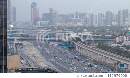Aerial view of Jumeirah lakes towers skyscrapers day to night timelapse with traffic on sheikh zayed road. 112974906