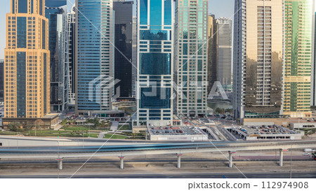 Aerial view of Jumeirah lakes towers skyscrapers timelapse with traffic on sheikh zayed road. 112974908