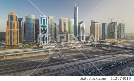 Aerial view of Jumeirah lakes towers skyscrapers timelapse with traffic on sheikh zayed road. 112974919