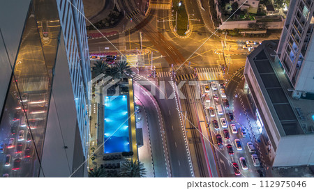 Aerial view of a road intersection in a big city night timelapse. Aerial view of a road intersection in a big city night timelapse. 112975046