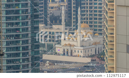 Al Raheem mosque between skyscrapers timelapse on the marina walk in Dubai Marina, Dubai, UAE. 112975117