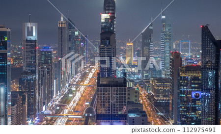Scenic Dubai downtown skyline at night timelapse. Rooftop view of Sheikh Zayed road with numerous illuminated towers. Scenic Dubai downtown skyline at night timelapse. Rooftop view of Sheikh Zayed road with numerous illuminated towers. 112975491