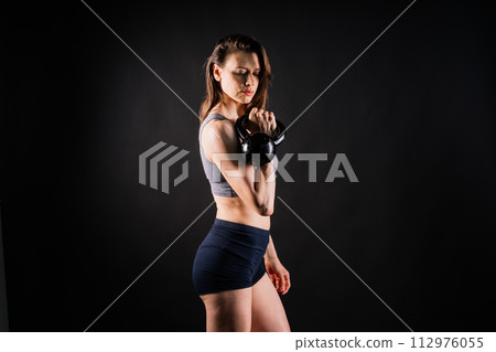 Young female doing swing exercise with a kettle bell. Fitness woman 112976055