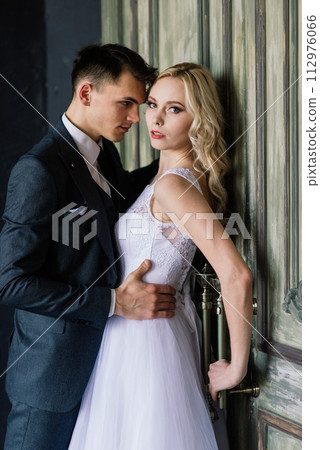 Cute wedding couple in the interior of a classic studio decorated. They kiss and hug each other. 112976066