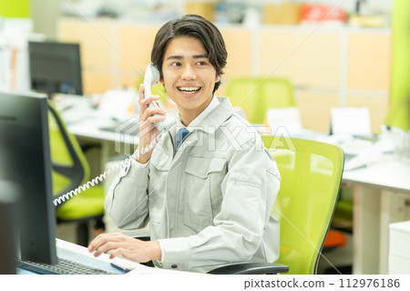 穿著工作服的年輕人在辦公室打電話 112976186