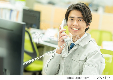 Young man in work clothes making a phone call in the office 112976187
