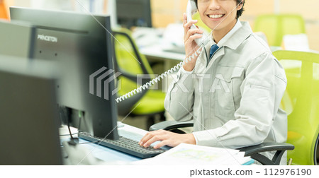 Young man in work clothes making a phone call in the office 112976190