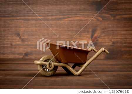 Miniature construction or garden wheelbarrow on wood texture background 112976618
