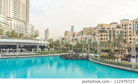 Pool and houses near the biggest musical fountain in Dubai at sunset timelapse. Dubai, UAE Pool and houses near the biggest musical fountain in Dubai at sunset timelapse. Dubai, UAE 112976727