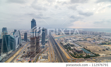 Dubai's business bay towers before sunset timelapse. Rooftop view of some skyscrapers and new towers under construction. 112976791