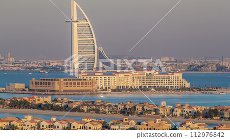 Dubai skyline with villas and Burj Al Arab during sunset timelapse. 112976842