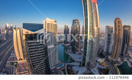 Buildings of Jumeirah Lakes Towers after sunset with traffic on the road day to night timelapse. Buildings of Jumeirah Lakes Towers after sunset with traffic on the road day to night timelapse. 112976946