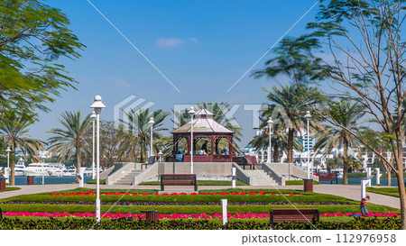 Alcove with green lawn, flowers and trees at Dubai Creek park timelapse. Dubai, United Arab Emirates 112976958